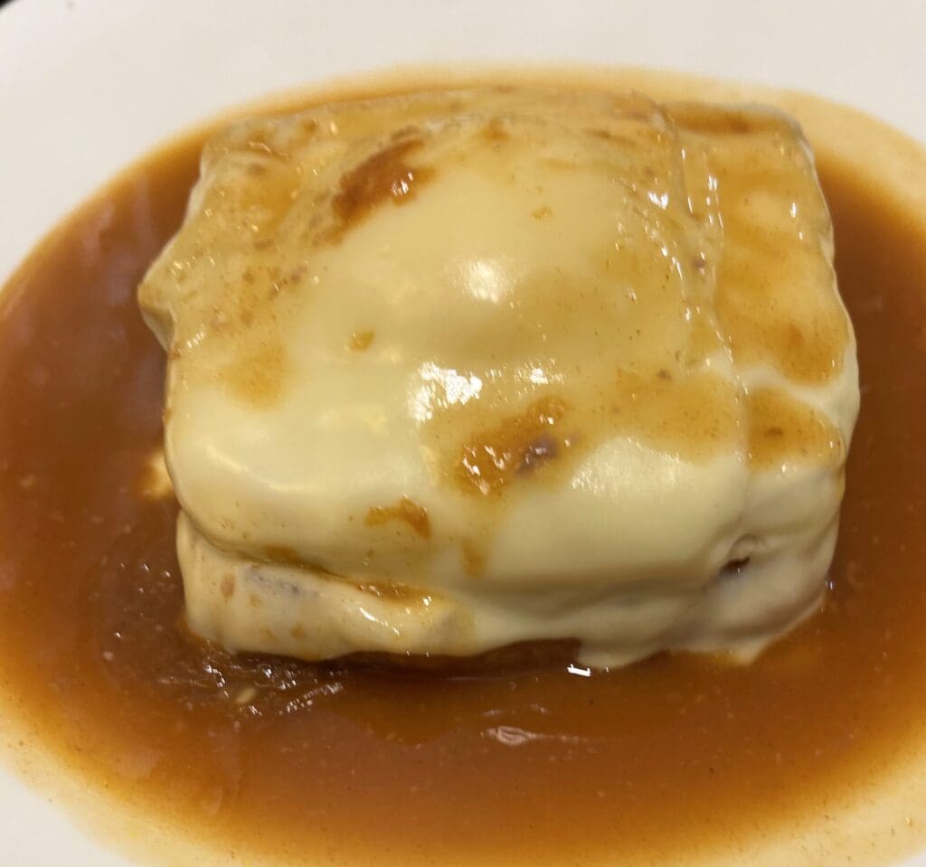 Traditional francesinha sandwich covered in melted cheese and beer sauce in Porto, Portugal