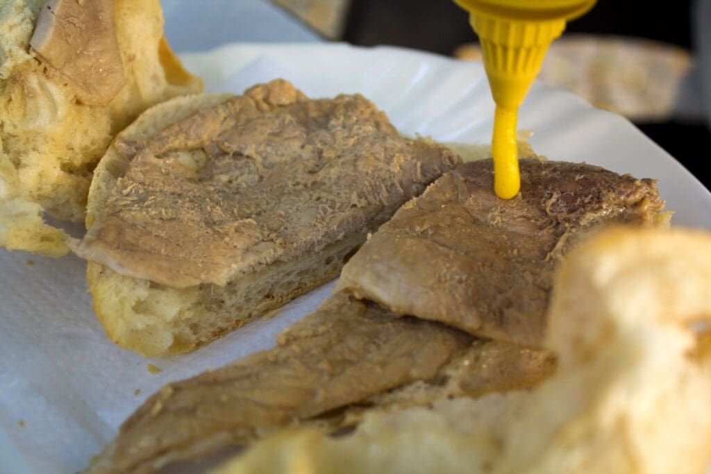 Adding mustard to a bifana sandwich in Lisbon Portugal