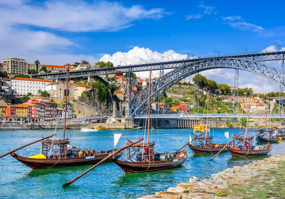 A scenic view of a historic iron bridge over a river with boats in the water.