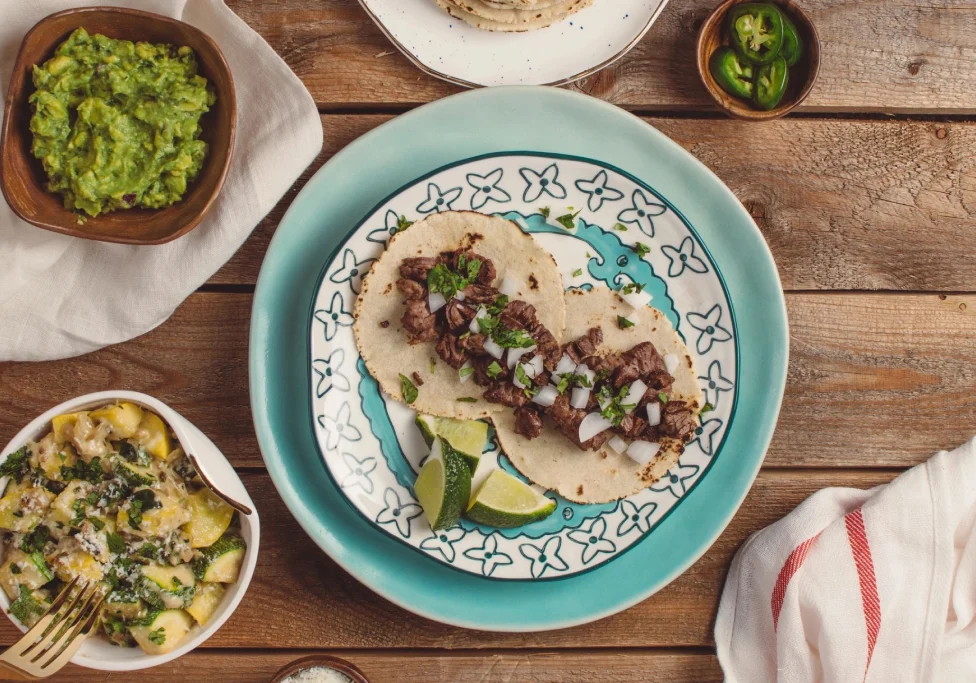Top view of a taco with meat and garnishes on a decorative plate.