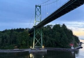 Cruise departing from Vancouver, Canada passing under the Lions Gate Bridge with Stanley Park and sunset in view