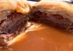 Francesinha sandwich cut open showing layers of meat, sausage and melted cheese with gravy at O Afonso restaurant in Porto Portugal