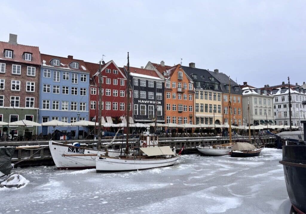 Colorful Nyhavn waterfront with boats frozen in the icy canal during winter in Copenhagen 2026