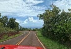 View over the hood of a red Jeep on Waimea Canyon Drive as the road curves toward the Pacific Ocean on Kauai's West Side