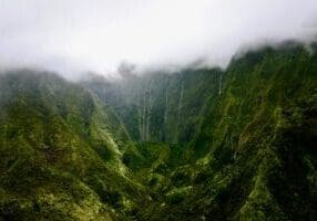The Weeping Wall's waterfalls streaming down Mount Waialeale's green cliffs in Kauai's misty interior, seen from the air