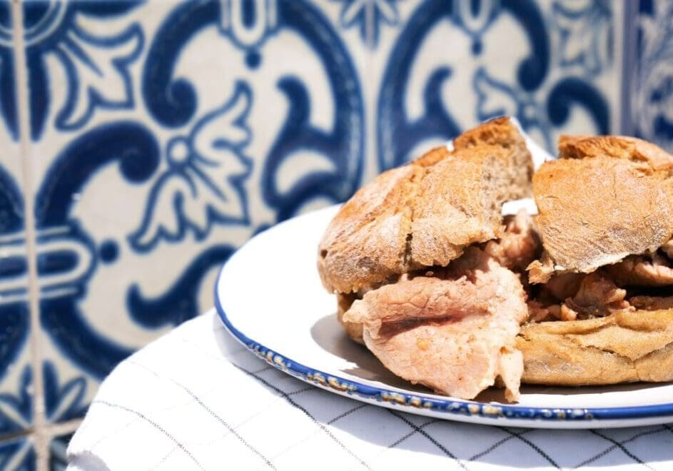 Bifana sandwich with pork on Portuguese blue tile table in Lisbon