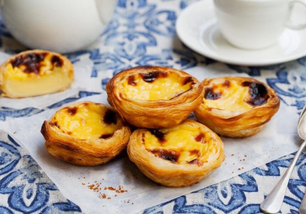 Pastel de nata Portuguese custard tarts on blue tile table in Lisbon